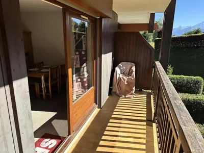 a person sitting on the porch of a house at Résidence Ecrin Des Glacier Aiglon - Ecrin des glaciers Aiglon 14 MAE-2783 in Combloux