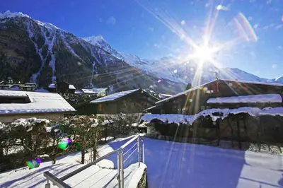 a view of a snow covered mountain with the sun at Chalet Couttet - Chamonix All Year in Chamonix-Mont-Blanc