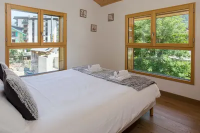 a bedroom with a large white bed with windows at Chalet Couttet - Chamonix All Year in Chamonix-Mont-Blanc