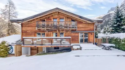 a group of wooden houses in a valley with mountains at Chalet Deutz in Chamonix-Mont-Blanc