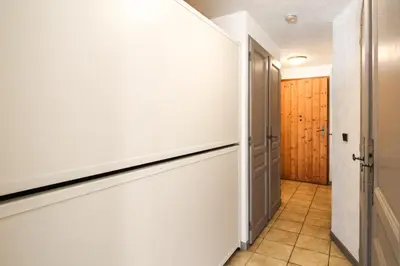a hallway with white walls and a door and a tile floor at Joli T2 Flaine Foret, oriente sud, linge & menage compris in Flaine