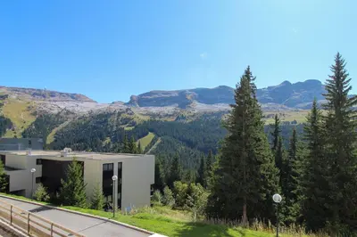 a building on the side of a road with mountains at Joli T2 Flaine Foret, oriente sud, linge & menage compris in Flaine