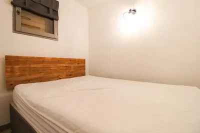 a small bedroom with a bed with a wooden headboard at Joli T2 Flaine Foret, oriente sud, linge & menage compris in Flaine