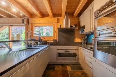 a kitchen with white cabinets and stainless steel appliances at Luxury Chalet Pool & Jacuzzi near Megeve in Sallanches