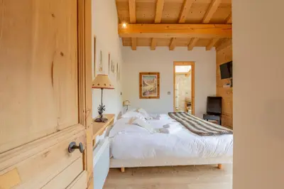 a bedroom with a white bed and a wooden ceiling at Luxury Chalet Pool & Jacuzzi near Megeve in Sallanches