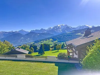 a house on a hill with mountains in the background at Appartement 2 chambres, vue Mont Blanc, parking inclus - FR-1-560-168 in Combloux