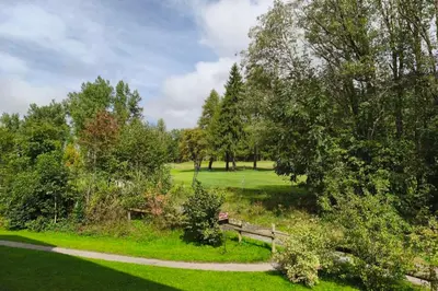 a park with a bench and trees and grass at Cozy apartment with pool and golf nearby in Megève
