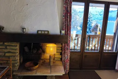 a living room with a fireplace and a window at Cozy apartment with pool and golf nearby in Megève