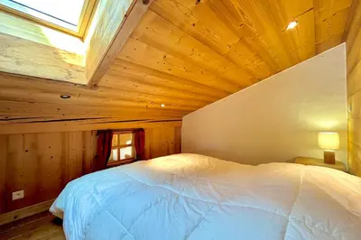 a bedroom with a white bed in a wooden room at Charming Alpine Apartment in Megève Mountain View in Megève