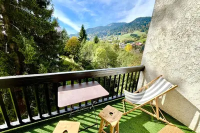 a balcony with a chair and a hammock on the grass at Charming Alpine Apartment in Megève Mountain View in Megève