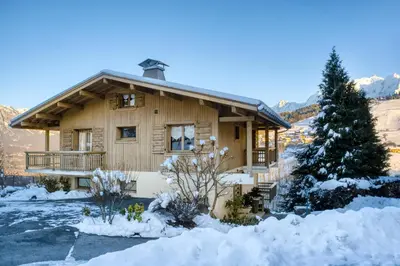 a log cabin in the snow with a christmas tree at Appartements dans le Chalet Nessa - Combloux in Combloux