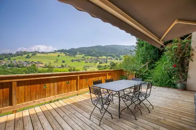 a patio with a table and chairs on a wooden deck at Appartements dans le Chalet Nessa - Combloux in Combloux