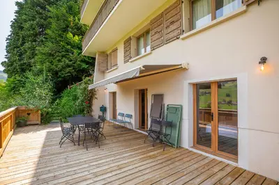 a wooden deck with a table and chairs on a house at Appartements dans le Chalet Nessa - Combloux in Combloux