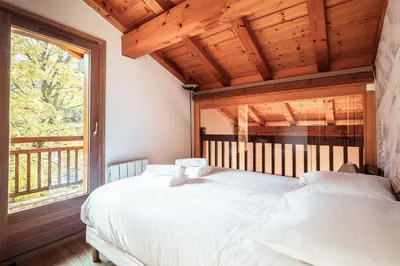 a bedroom with a large white bed and a window at Les Cimes d'Eden - Cozy duplex in Megève in Megève