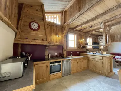 a kitchen with wooden cabinets and a clock on the wall at Chalet spacieux à Samoëns, 6 chambres, idéal pour 14 personnes avec Wifi - FR-1-846-1 in Samoëns