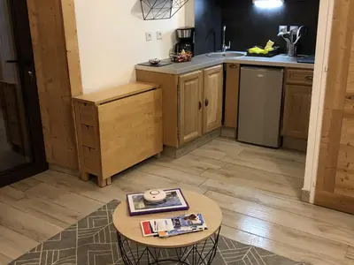 a kitchen with wooden cabinets and a table with a magazine at Studio cosy pour 4 à Samoëns - FR-1-846-4 in Samoëns