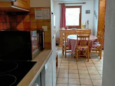 a kitchen with a table and a dining room at Appartement cosy 2 pièces avec Wifi à Samoëns - FR-1-846-10 in Samoëns
