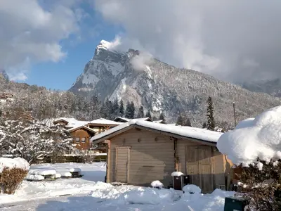 a snow covered building with a mountain in the background at Appartement cosy 2 pièces avec Wifi à Samoëns - FR-1-846-10 in Samoëns