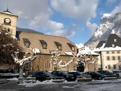 a building with cars parked in a parking lot with a clock tower at Appartement cosy 2 pièces avec Wifi à Samoëns - FR-1-846-10 in Samoëns