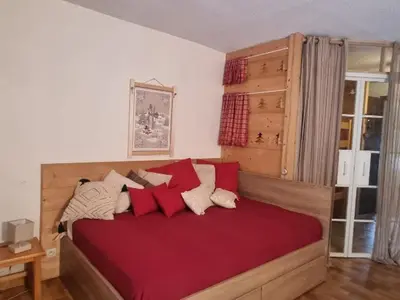 a bedroom with a bed with red sheets and pillows at Appartement cosy avec Wifi à l'orée du bois - FR-1-846-11 in Samoëns