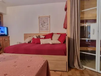 a bedroom with a large bed with red sheets at Appartement cosy avec Wifi à l'orée du bois - FR-1-846-11 in Samoëns
