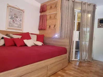 a bedroom with a large bed with red sheets at Appartement cosy avec Wifi à l'orée du bois - FR-1-846-11 in Samoëns