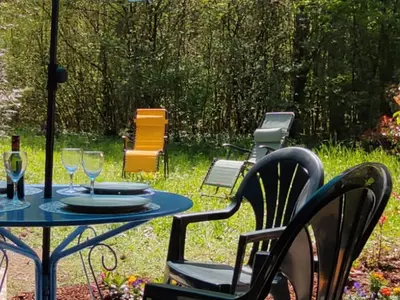 a table with wine glasses and chairs in a yard at Appartement cosy avec Wifi à l'orée du bois - FR-1-846-11 in Samoëns