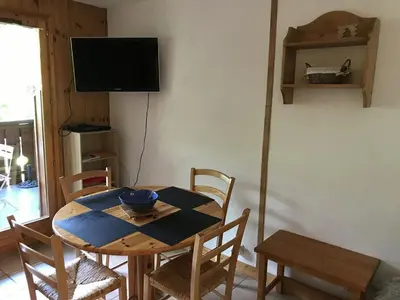 a dining room with a table with chairs and a television at Charmant appartement avec WiFi à Samoëns - FR-1-846-20 in Samoëns