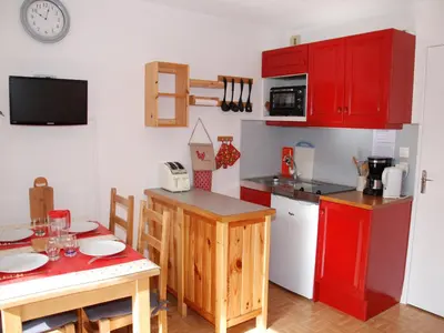 a kitchen with red cabinets and a small table with a tableablish at Studio cosy pour 4 personnes à Samoëns - FR-1-846-31 in Samoëns