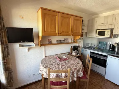 a small kitchen with a small table with chairs and a microwave at Studio Samoëns - 4 pers, cosy & pratique - FR-1-846-33 in Samoëns