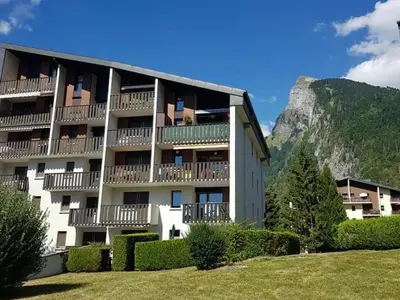 a building with balconies and bushes in front of a mountain at Charmant appartement avec Wifi à Samoëns - FR-1-846-35 in Samoëns