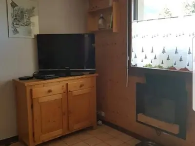 a television on a wooden stand in a room with a window at Charmant appartement avec Wifi à Samoëns - FR-1-846-35 in Samoëns