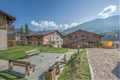 a park with benches and a playground with buildings at Appartement Prariand - Welkeys in Megève