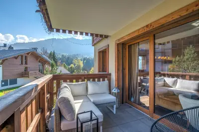 a porch with a couch and chairs on a balcony at Appartement Prariand - Welkeys in Megève