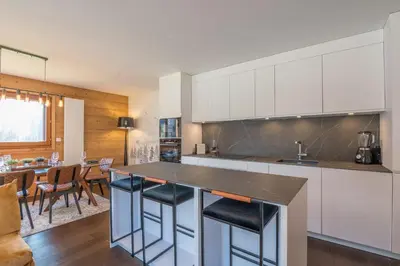 a kitchen with white cabinets and a counter with stools at Appartement Prariand - Welkeys in Megève