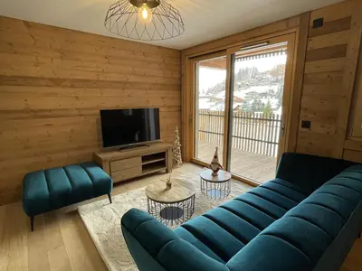 a living room with a blue couch and a television at Appartement de standing 3 chambres au centre, pied de piste, parking et WIFI - FR-1-836-5 in Arâches-la-Frasse