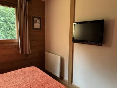 a bedroom with a flat screen tv on the wall at Appartement de standing 6 pers avec piscine et parking - FR-1-836-3 in Arâches-la-Frasse