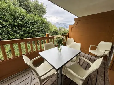 a table and chairs on a deck with a view at Appartement de standing 6 pers avec piscine et parking - FR-1-836-3 in Arâches-la-Frasse