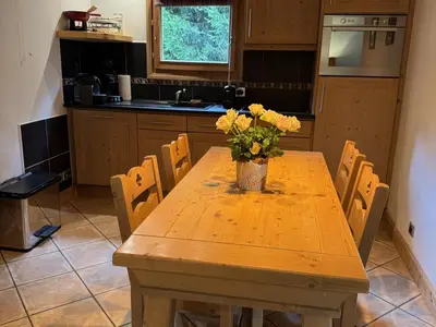 a kitchen with a wooden table with a vase of flowers on it at Appartement de standing 6 pers avec piscine et parking - FR-1-836-3 in Arâches-la-Frasse