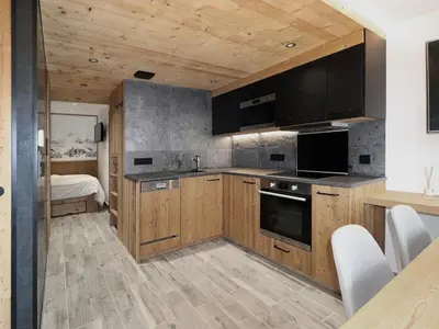 a kitchen with wooden cabinets and a bed in a room at Appartement central 1 chambre, 4 pers, WIFI, garage - FR-1-836-12 in Arâches-la-Frasse