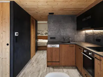 a kitchen with wooden cabinets and a bed in the background at Appartement central 1 chambre, 4 pers, WIFI, garage - FR-1-836-12 in Arâches-la-Frasse