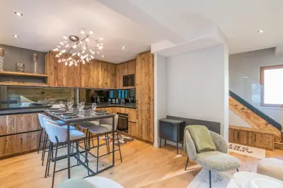 a kitchen with wooden cabinets and a table with chairs at Duplex Veyra - Welkeys in Megève