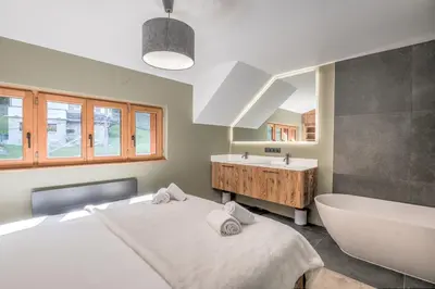 a bathroom with two beds and a tub and a sink at Duplex Veyra - Welkeys in Megève