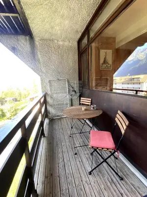 a wooden deck with a table and two chairs at Charmant studio Chamonix in Chamonix-Mont-Blanc