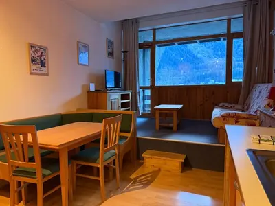 a room with a table and chairs and a bedroom at Charmant studio Chamonix in Chamonix-Mont-Blanc