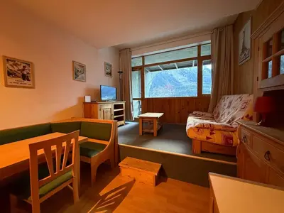 a living room with a couch and a table and a window at Charmant studio Chamonix in Chamonix-Mont-Blanc