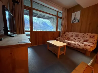 a living room with a couch and a large window at Charmant studio Chamonix in Chamonix-Mont-Blanc