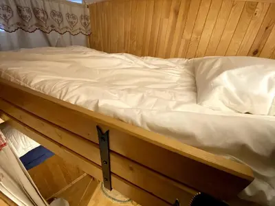 a bed with white sheets on top of a room at Charmant studio Chamonix in Chamonix-Mont-Blanc