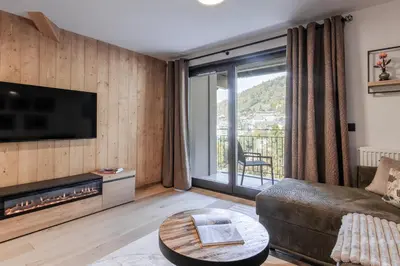 a living room with a couch and a large window at Alpine Bliss - Sources, Ski in Saint-Gervais-les-Bains