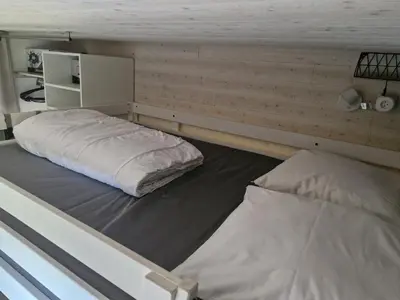 a room with two beds in a room with a wall at Studio rénové pour 4 au pied de la piste de luge - FR-1-836-13 in Arâches-la-Frasse